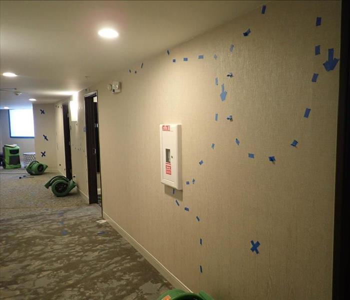 Drying equipment on floor and tape markings on wall.